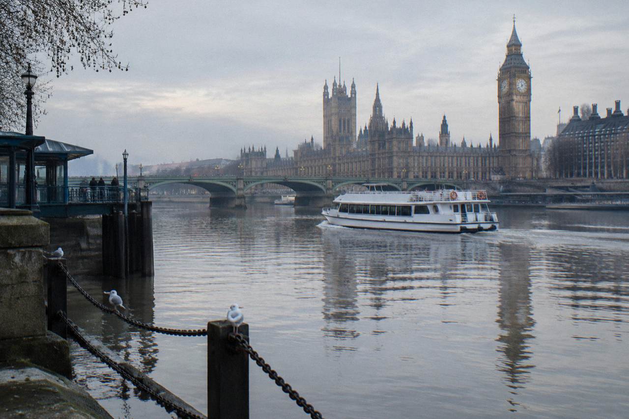 A passenger boat on the River Thames passing under a bridge on a calm winter morning