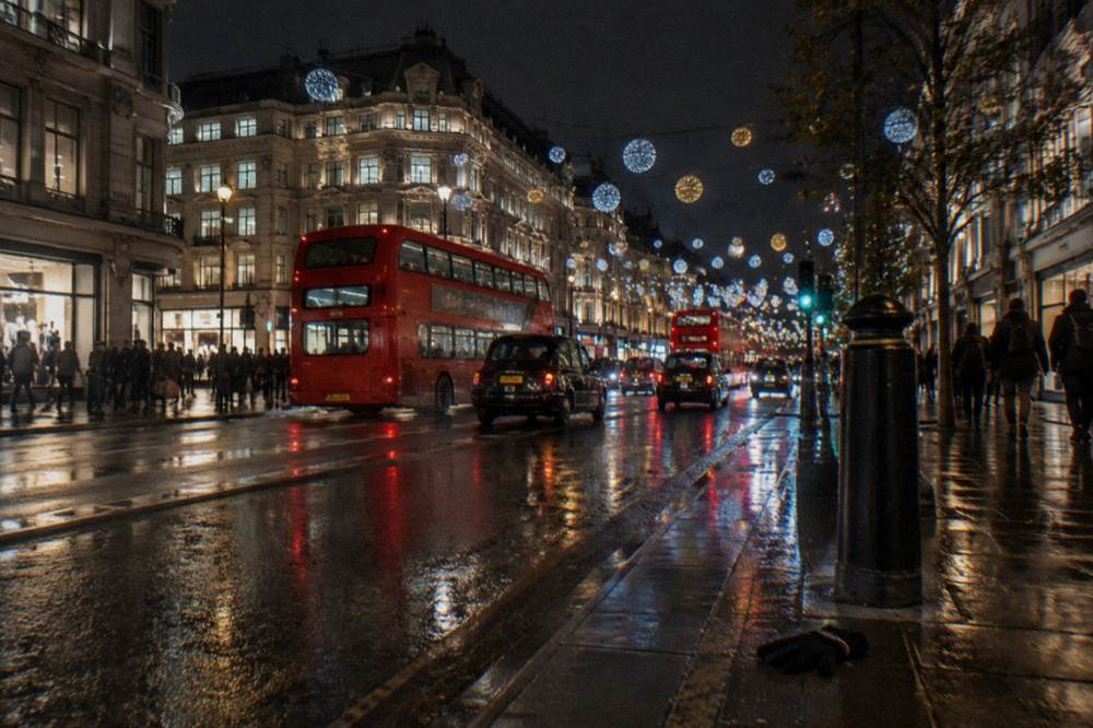 Colourful illuminated Christmas lights strung across a busy city street at night