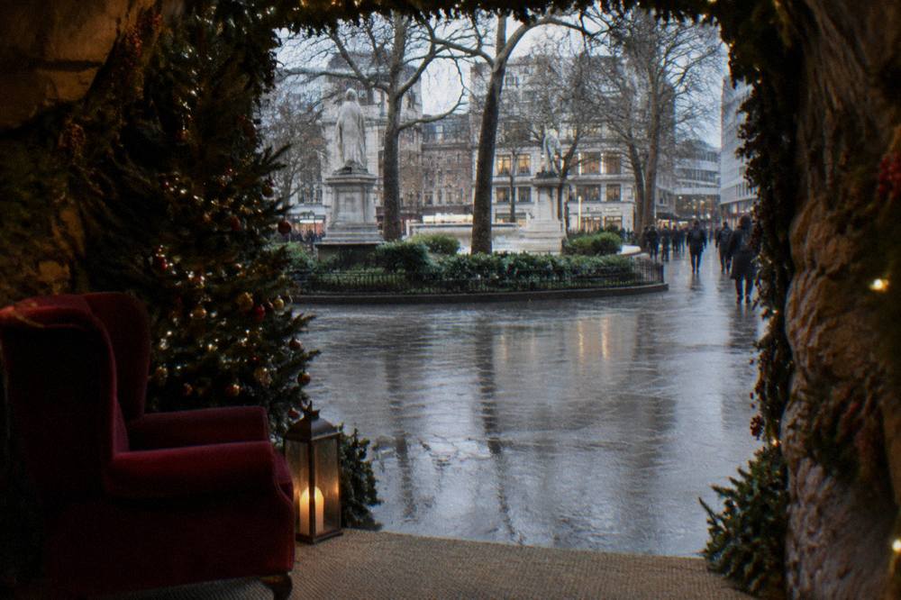 A museum grotto doorway with garlands, a red velvet chair and a lantern beside a Christmas tree