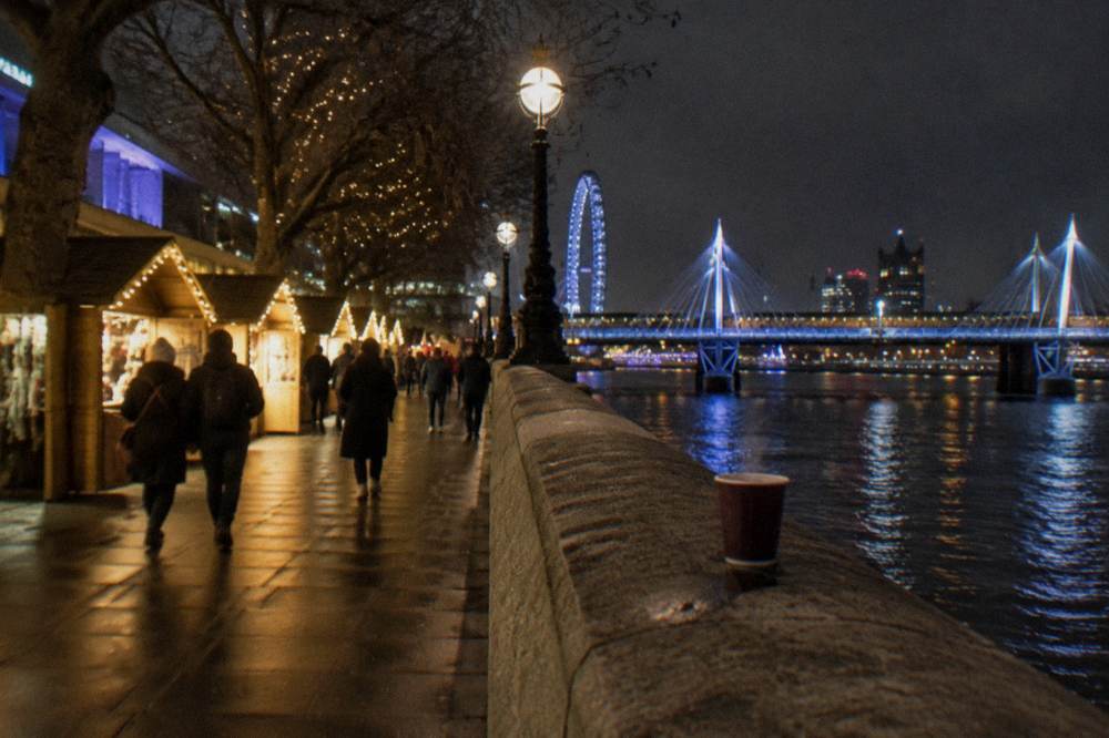 Illuminated bridges over the Thames seen from a riverside walk at night