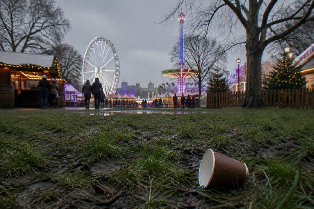 Fairground rides and glowing light displays in a park at dusk