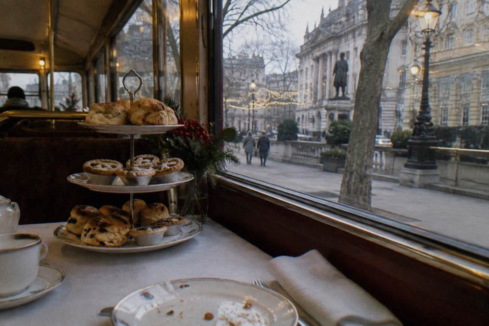 Festive afternoon tea spread on a table beside a window overlooking a decorated street