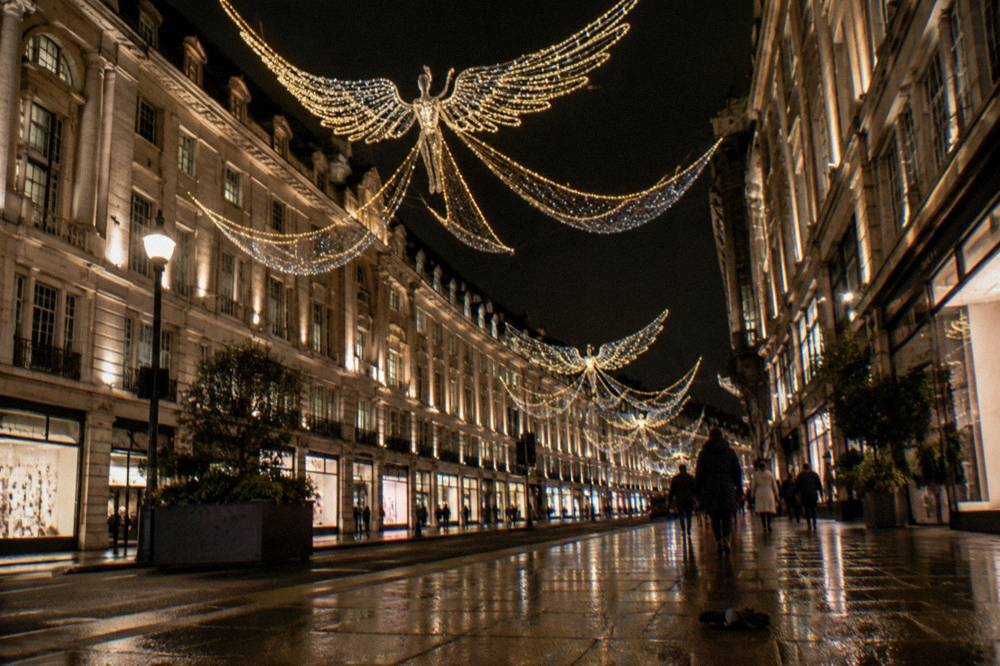 Illuminated angels light display suspended across a wide shopping street at night