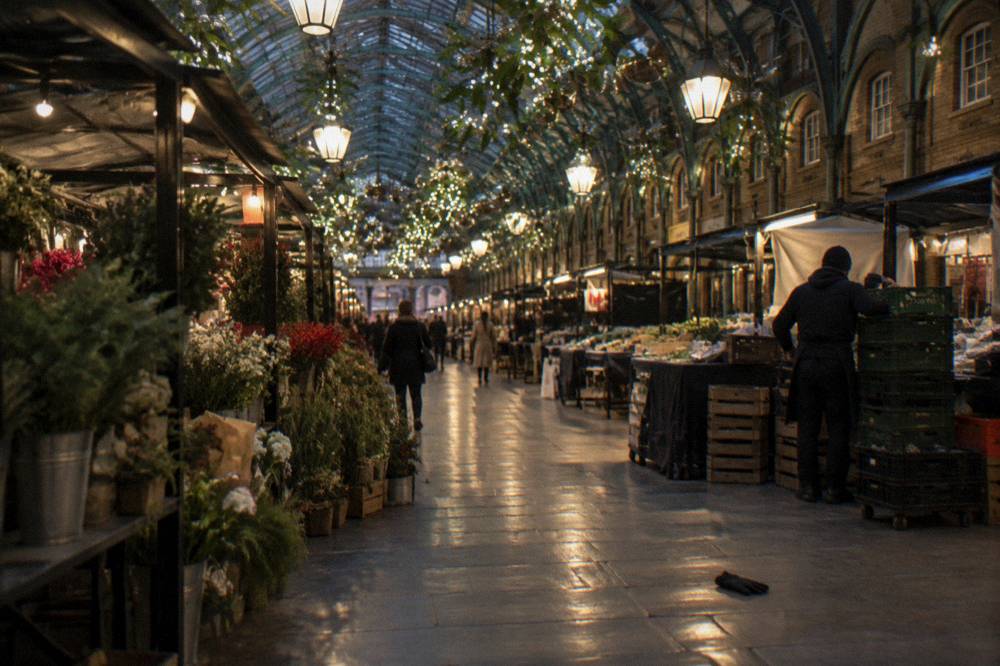 A covered market courtyard decorated with hanging lights and festive ornaments at night