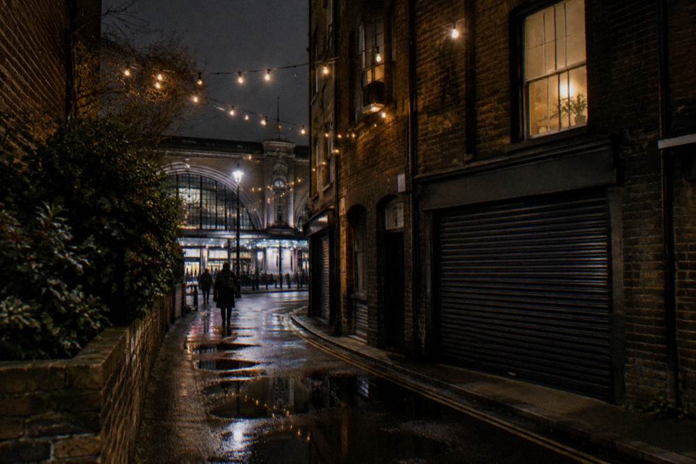 A quiet London side street with strings of festive lights strung between buildings at night
