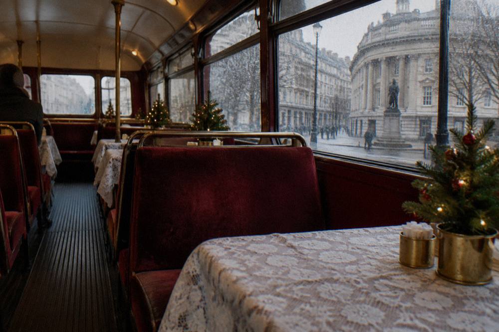 A festively decorated interior of a vintage double decker bus with small Christmas trees on the tables