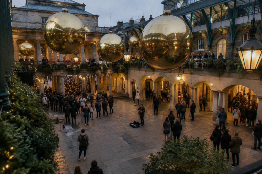 Christmas lights and a large decorated tree above a covered market square in the evening