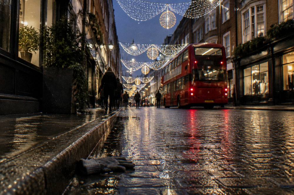 City street at night with festive lights above the road and a bus in traffic