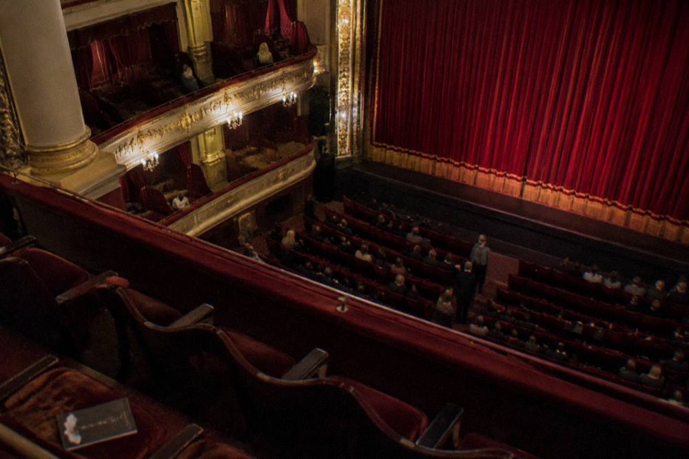 Theatre auditorium with a red curtain and empty seats before a performance
