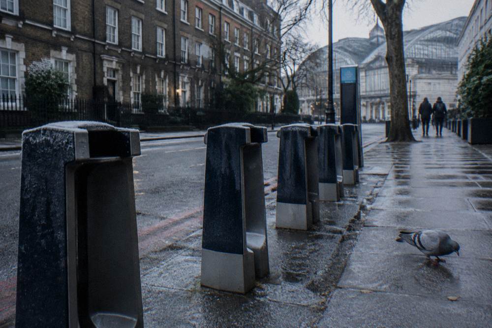 Red bicycles docked at a hire station beside a quiet London street