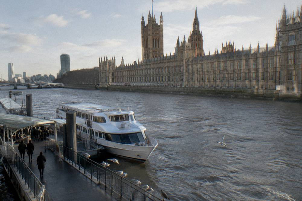 River boat moored at a London pier with the Houses of Parliament behind in winter light