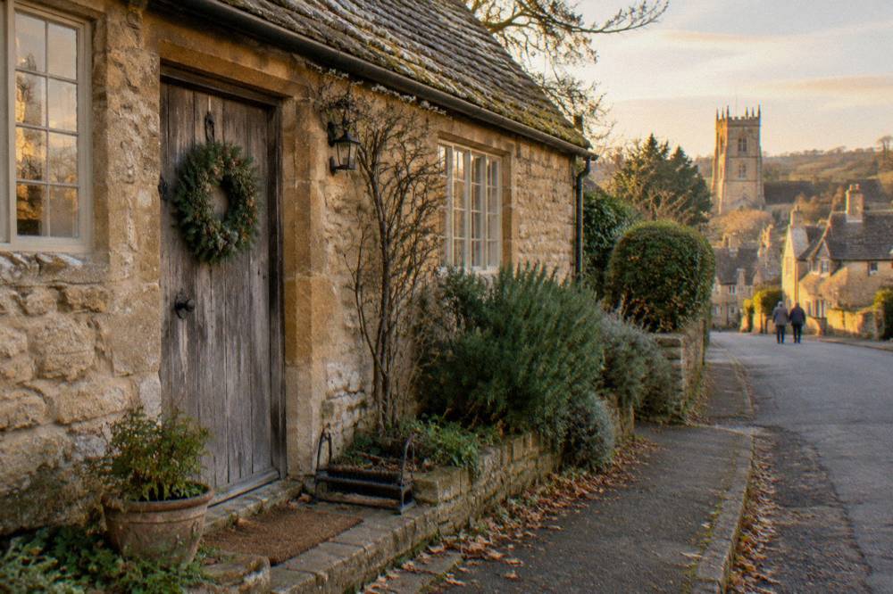 A stone Cotswolds cottage with a wreath on a wooden door