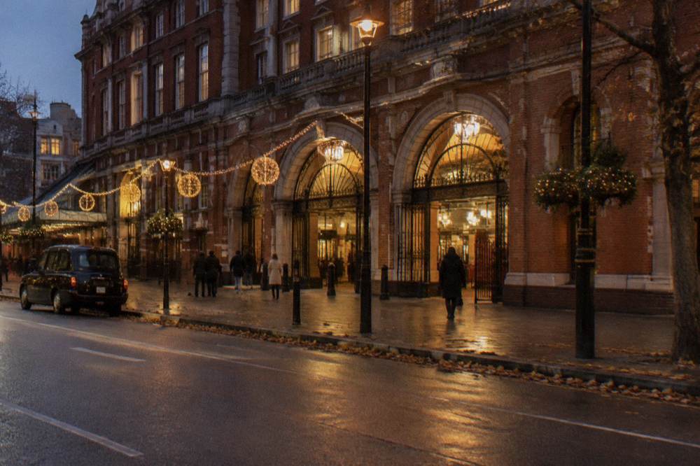 London Underground station entrance lit at night with a quiet street and festive lights in the background