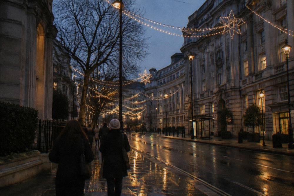 A small group of walkers on a decorated London pavement looking up at illuminated festive displays