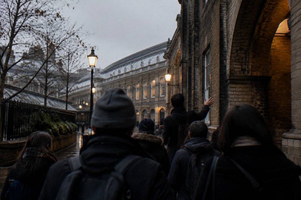 Tour guide speaking to a small group gathered on a London street in the late afternoon