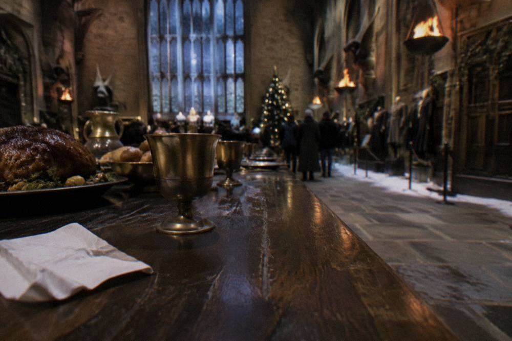 Snow covered Great Hall tables dressed for a festive feast under warm lighting