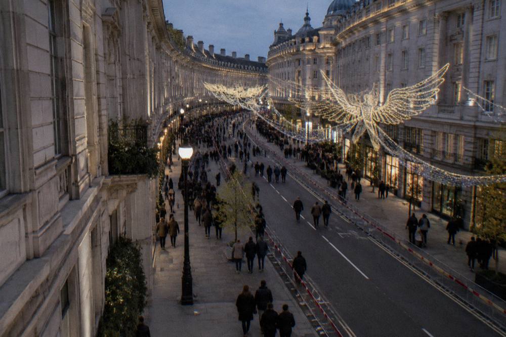 A lit shopping street in London in the evening with festive decorations overhead