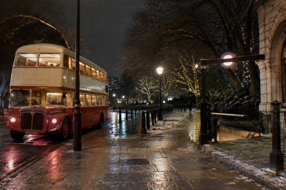 A vintage double-decker bus travelling along a decorated city street at night