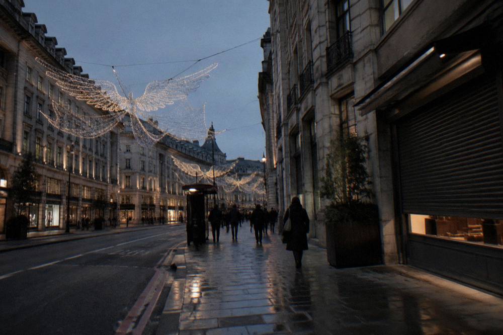 Christmas lights glowing on a London shopping street at dusk in early afternoon darkness