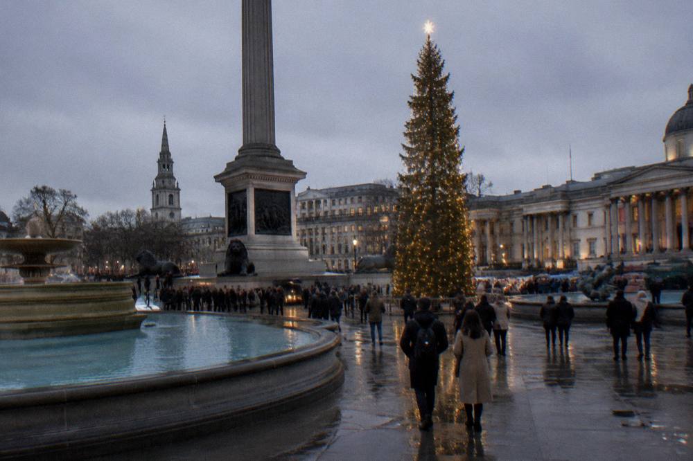 A lit Christmas tree and crowded festive street in London in the early evening