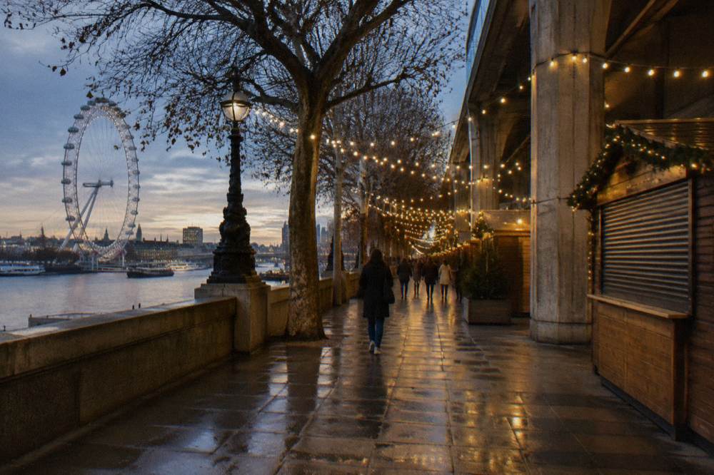 A quiet high street in London at dusk with festive lights strung between buildings