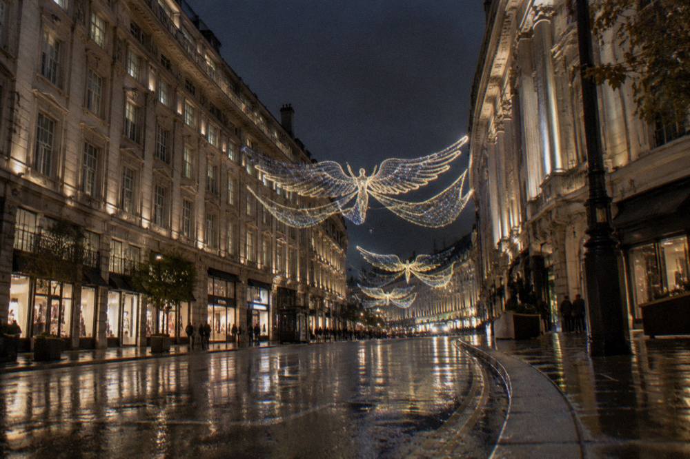 Illuminated shopping street in the West End at night with bright festive displays above the road