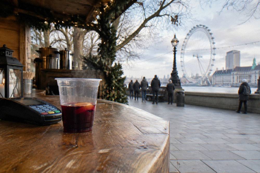 Wooden market chalets with festive garlands and lights along a riverside walkway in London